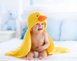 Ein Baby trägt die Kapuze eines gelben Bademantels, die einem Entenkopf ähnelt.