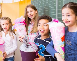 Schüler stehen zum ersten Schultag mit ihren Schultüten vor einer Tafel.