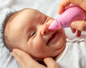 Einem Baby wird mit einem Nasensauger der Nasenschleim herausgesaugt.