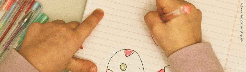 Kind zeichnet mit einem Stift rote Herzen in sein Heft.
