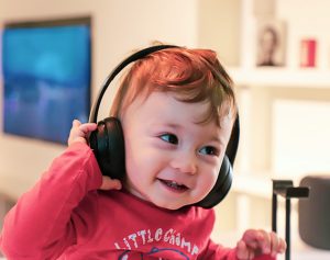 Ein Kleinkind trägt große schwarze Kopfhörer auf seinem Kopf.