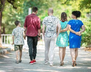 Ein Junge, zwei Männer ein Teenager und eine Frau gehen nebeneinander durch einen Park.